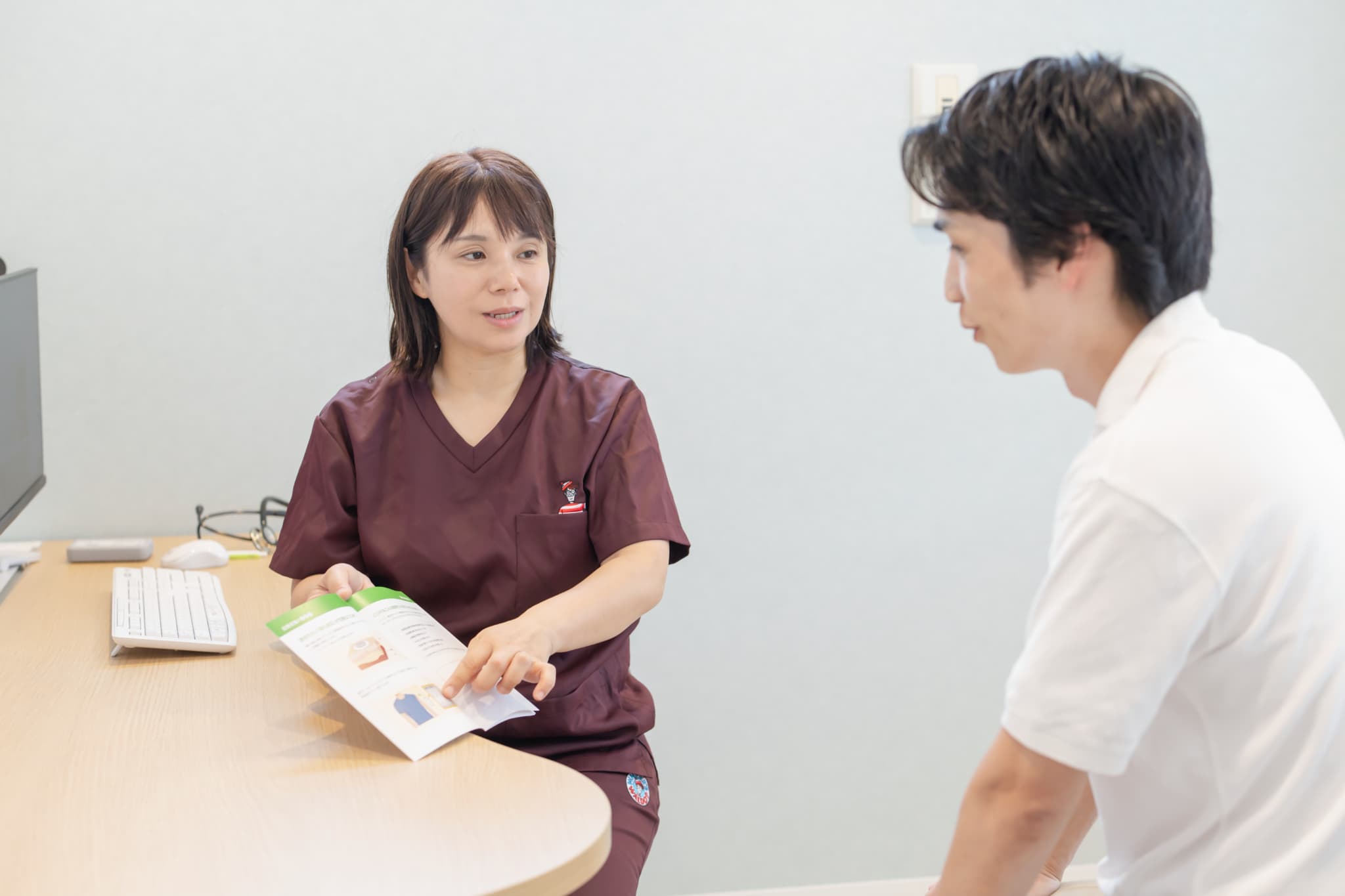 女性医師がパンフレットを使って患者に治療内容を説明する診察の様子