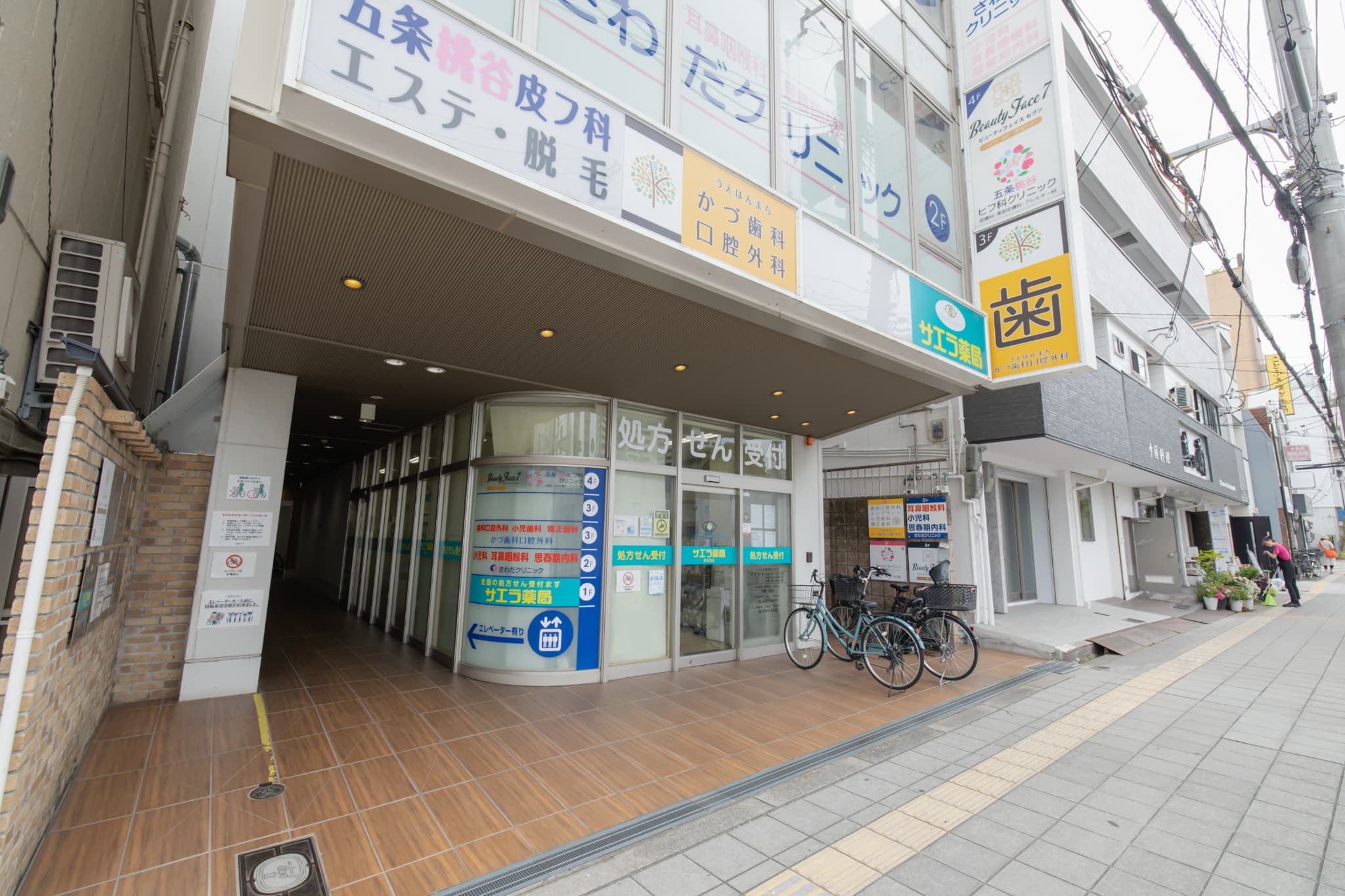 歯科・皮フ科・小児科・薬局などが入った医療ビルの入口と処方せん受付・各院の看板